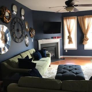 A cozy living room with a sofa, tufted ottoman, and decorative wall elements.