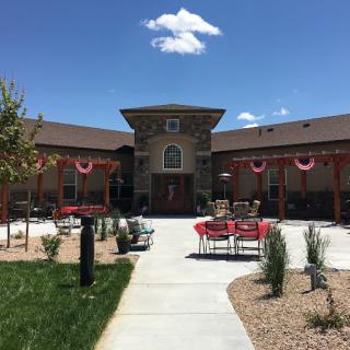 A building with a courtyard featuring outdoor seating and landscaping under a clear blue sky.
