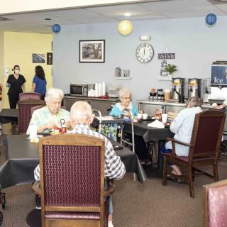 A group of elderly individuals enjoying a meal together in a communal dining space.
