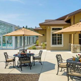 A sunny patio area with tables, chairs, and umbrellas next to a modern building.