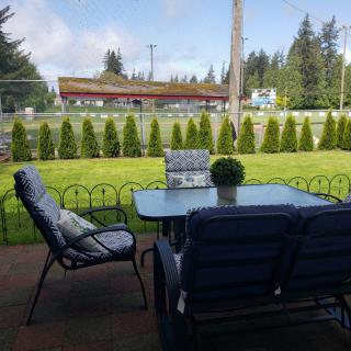 A cozy patio setup with cushioned chairs and a glass table overlooking a well-kept garden.