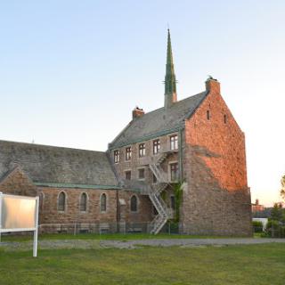 A historic building featuring a church spire, illuminated by the warm light of sunset.