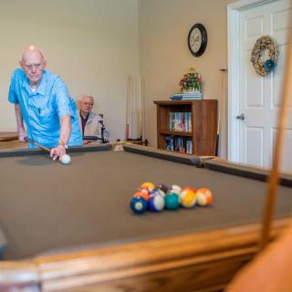 A person prepares to take a shot on a pool table in a game room.