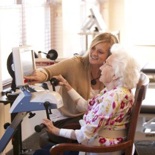 A caregiver assisting an elderly woman with using a computer.