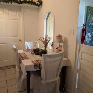 A cozy dining area featuring a neatly set table with flowers and a mirror, creating an inviting atmosphere.