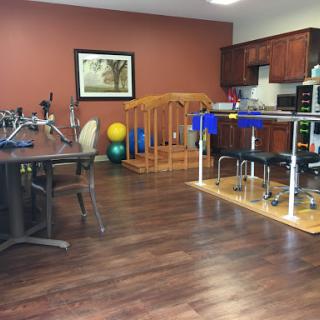 A spacious therapy room equipped with various rehabilitation tools and exercise equipment.