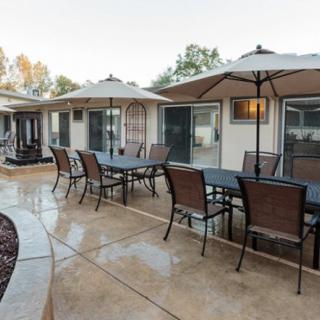 A residential patio with multiple tables and chairs under umbrellas, set on a wet pavement.