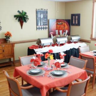 A neatly arranged dining room with a buffet setup and elegantly set tables adorned with flowers.
