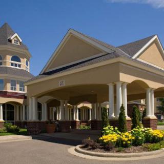 The elegant entrance of a hotel, featuring beautiful architecture and vibrant landscaping against a clear blue sky.