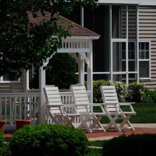 A serene outdoor space featuring white lawn chairs arranged near a gazebo, perfect for relaxation.