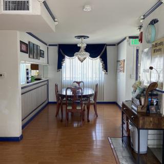 A dining room with a round table and chairs, featuring blue curtains and accents against a hardwood floor.