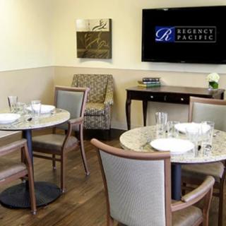 A cozy dining area with neatly arranged tables and chairs, featuring a television on the wall.