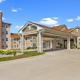 A residential building with a covered entrance and driveway under a clear blue sky.
