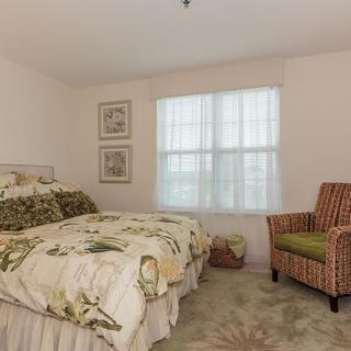 A cozy bedroom with a floral-patterned bedspread and a striped armchair by the window.