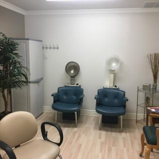 A modern salon waiting area with blue chairs and hair dryers.