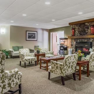 A cozy lobby area with patterned chairs, wooden tables, and a fireplace.
