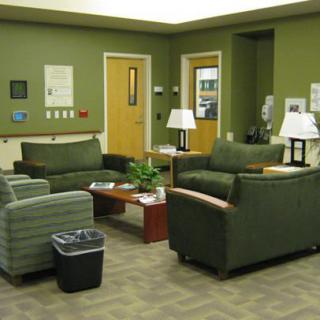 A quiet waiting room with green walls and comfortable seating.