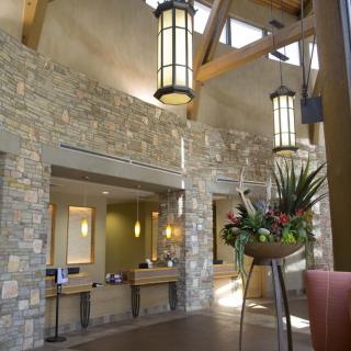 A modern lobby featuring stone walls, elegant lighting, and a decorative floral arrangement.