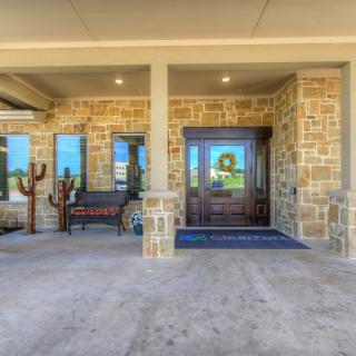A welcoming stone exterior entrance with a bench and decorative cactus.