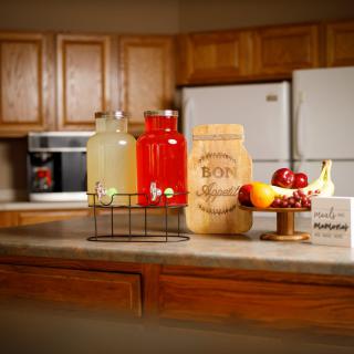 A cozy kitchen countertop featuring juice bottles and a decorative fruit arrangement.