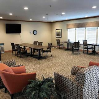 A well-lit conference room with a large table, chairs, and a television.