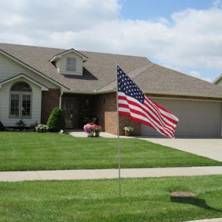A beautiful suburban home displaying an American flag on a sunny day.