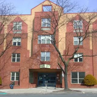 A four-story brick residential building with several windows and a central entrance.