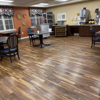 An empty dining area with wooden floors, tables, and chairs.