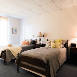 A cozy bedroom with twin beds, decorated with colorful pillows and lit by table lamps.