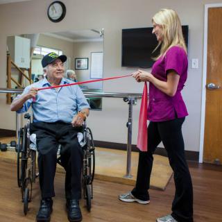 A therapist assists a man in a wheelchair during a rehabilitation exercise session.
