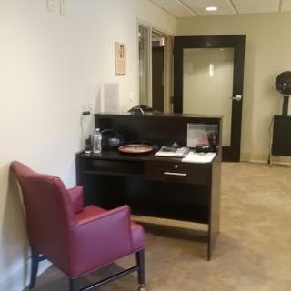 A cozy office waiting area featuring a red chair and a desk.