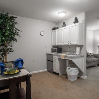 A cozy kitchen with a small dining area, featuring white cabinets and a table set for two.