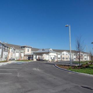 A wide-angle view of a large building with an empty driveway and clear blue sky.