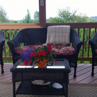 A cozy patio setup with wicker chairs, a table adorned with flowers, and scenic outdoor views.