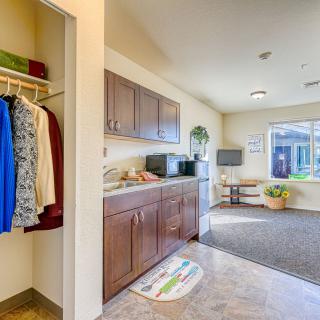 A cozy open-plan kitchen and living space with cabinetry, appliances, and a closet, bathed in natural light from a large window.