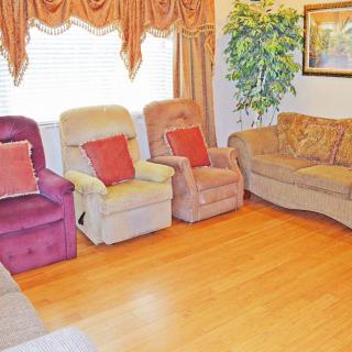 A cozy living room with a sofa, reclining chairs, and hardwood flooring.