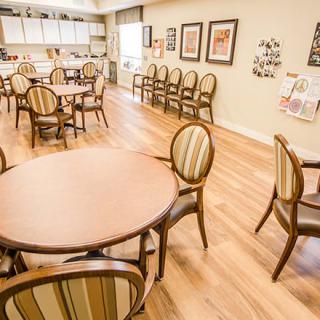A well-lit dining area with neatly arranged tables and chairs on a wooden floor.