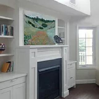 A cozy living room with a fireplace, art piece, and built-in shelves.