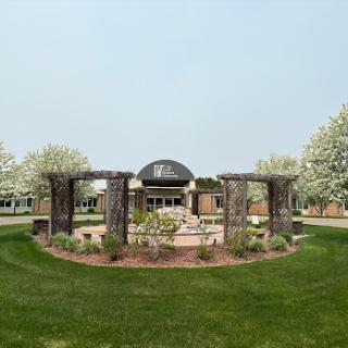 A serene garden setting featuring a central fountain, surrounded by vibrant greenery and flowering trees.
