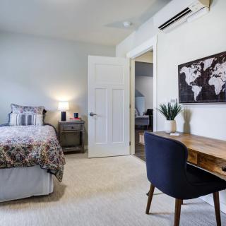 A modern minimalist bedroom with a neatly arranged desk and map artwork on the wall.