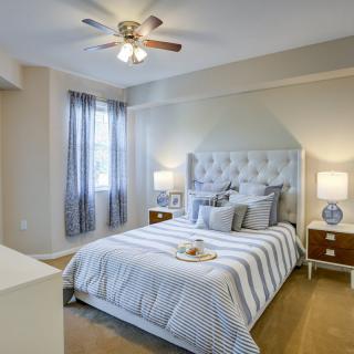 A cozy, elegantly decorated bedroom with a tufted headboard and striped bedding.