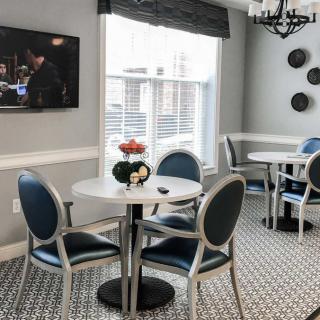 A cozy dining area with round tables, modern chairs, and a television on the wall.
