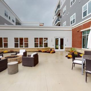 A modern outdoor patio with comfortable seating, surrounded by an apartment building.