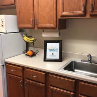 A cozy kitchen countertop with a fruit basket and framed artwork next to the sink.