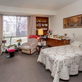 A cozy bedroom featuring a neatly made bed, comfortable seating, and plenty of natural light.