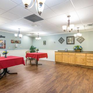 A spacious dining area featuring tables with red tablecloths and warm wooden accents.