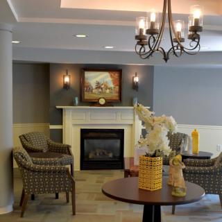 A cozy living room with a fireplace, elegant chandelier, and comfortable seating arrangement.