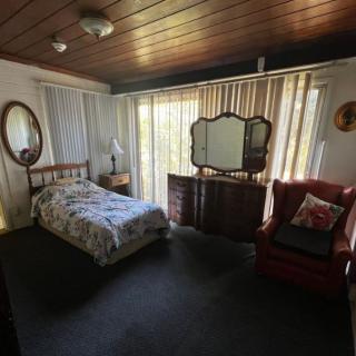 A cozy bedroom with vintage decor featuring a single bed, an ornate mirror, and comfortable seating.
