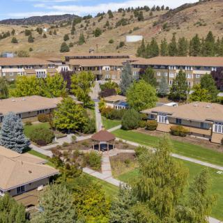 Aerial view of a housing complex surrounded by lush greenery and hills.
