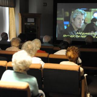 A group of elderly people watching a movie in a small theater.